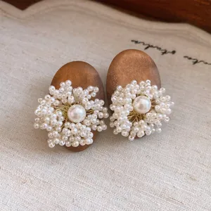 Macro view of vintage style wooden earrings featuring intricate pearl flower clusters