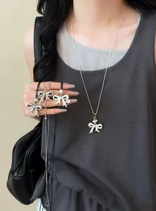 Close-up of a stylish silver bow pendant necklace with adjustable leather cord on model