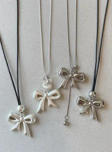 Detailed view of four different bow pendant necklaces featuring leather cords and silver chains.