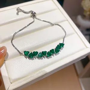 Detailed view of silver adjustable bracelet featuring sparkling green heart-shaped zircons