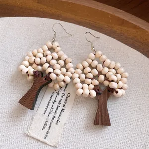 Close-up of tree-shaped earrings crafted with wooden beads and dark wood trunks