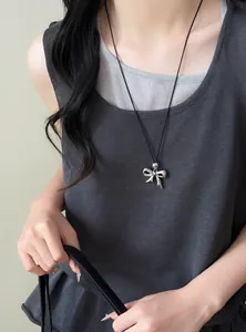 Detailed view of a stylish silver bow pendant necklace with a black cord on a fashion model.