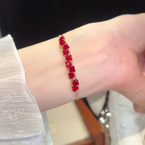 Close-up view of elegant 18k gold plated heart bracelet with red zircons on wrist.