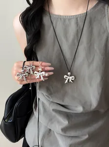 Detailed view of bow pendant necklaces with leather cord and silver finish charms.