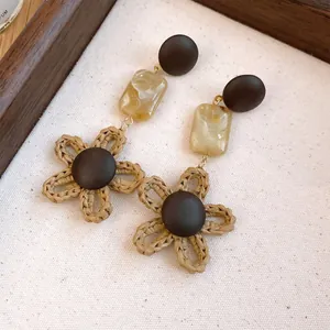Close-up of retro bohemian earrings with wooden studs and handmade straw flower drops