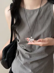 Detailed view of the matte white bow necklace with a pearl accent on a model.