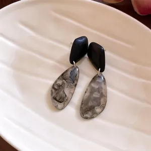 Close-up of vintage resin earrings with grey marble ink pattern teardrop pendants