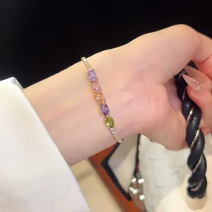 Detail of 18K gold plated bracelet with multi-colored oval zircons on woman's wrist