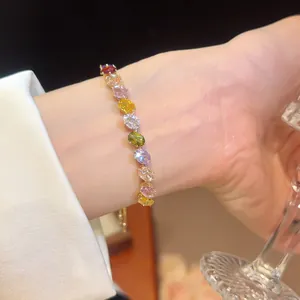 Close-up of sparkling multi-colored oval zircon bracelet on wrist with gold finish