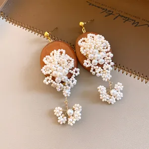 Close-up of vintage wooden earrings featuring intricate pearl beadwork and dangles