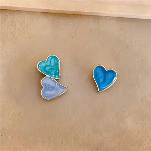 Detailed macro view of asymmetrical heart stud earrings with blue and purple enamel