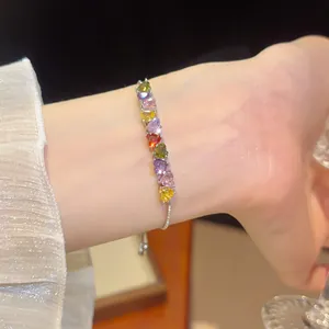 Heart-shaped colorful zircon bracelet with 18k gold plating on a person's wrist.