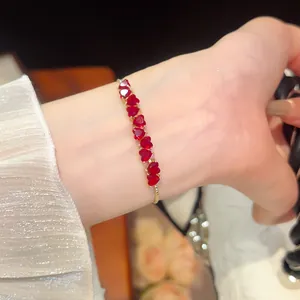Close-up of gold-plated bracelet featuring vibrant red heart-shaped zirconia stones.