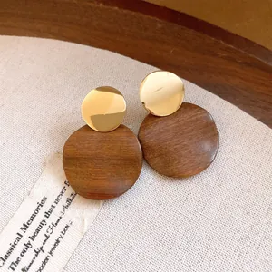 Close-up detail of vintage wooden stud earrings with gold circular metallic tops