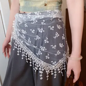 Close-up of white floral lace mesh waist scarf tied over a dark grey skirt