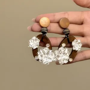Detaillierte Nahaufnahme von Retro-Holzohrringen mit zarten weißen Blumendekorationen