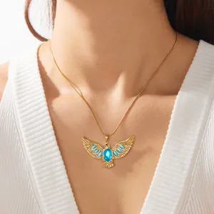 Detailweergave van de gouden adelaarsketting met blauwe edelsteen om de nek