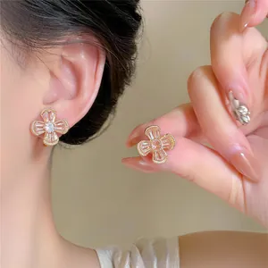 Close-up detail of sparkling zircon flower ear clips with an elegant gold finish for women