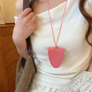 Détail d'un collier porte-lunettes magnétique en cuir rose sur un haut d'été blanc