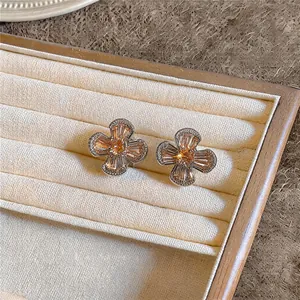 Close-up of elegant orange zircon flower earrings displayed on a white velvet jewelry tray