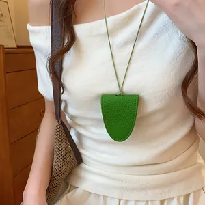 Élégant collier porte-lunettes magnétique en cuir vert sur un haut en tricot blanc