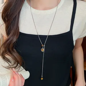 Gros plan d'un collier avec perles et pendentif étoile sur une longue chaîne argentée.