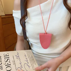 Détail d'un collier porte-lunettes magnétique en cuir rose porté comme accessoire chic