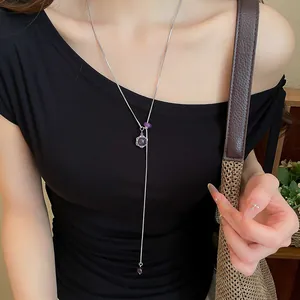 Détail d'un long collier hexagramme argenté avec des perles violettes et pierres