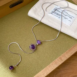Gros plan sur un collier hexagramme minimaliste avec des perles violettes