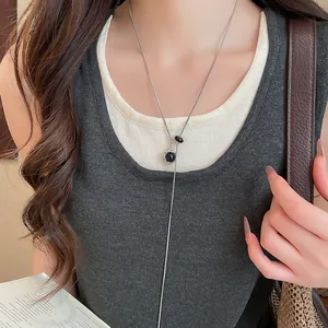 Gros plan d'un collier argenté minimaliste avec pendentif étoile hexagramme noire sur modèle.