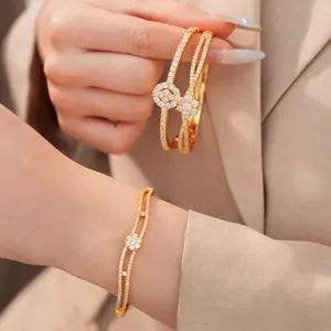 Detailaufnahme eines 18K vergoldeten Blumenarmreifs mit Zirkonia am Damenhandgelenk