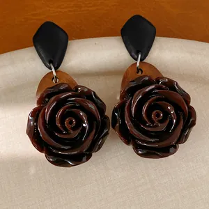 Detailansicht von Vintage-Ohrringen mit Holz und dunkelbraunen Rosen aus Harz auf Stoff