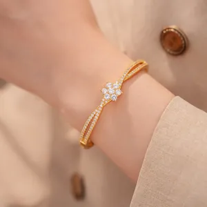 Nahaufnahme eines 18K vergoldeten Armreifs mit Zirkonia-Blume im Kreuzdesign