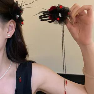 Dettaglio di un fermaglio per capelli gotico con mano di scheletro, fiore e nappe rosse.