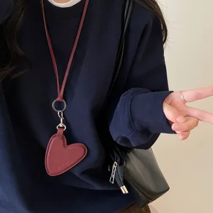 Gros plan d'un pendentif cœur en cuir bordeaux avec cordon sur un sweat bleu marine chic