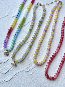 Detailed view of multiple colorful dopamine beaded necklaces with crystal pendants