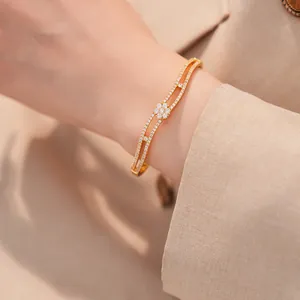 Detaillierte Nahaufnahme eines vergoldeten Zirkonia-Blumenarmbands am Handgelenk.