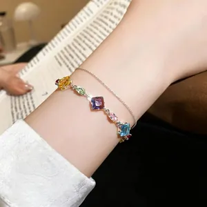 Detailed view of candy colored zircon geometric bracelet worn on a female model's wrist