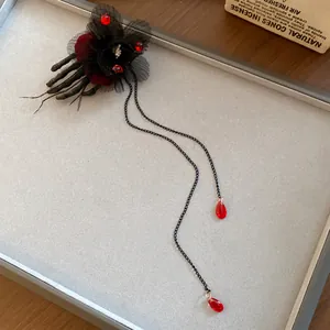 Dettaglio di un fermaglio per capelli a mano di scheletro gotico con nappe rosse eleganti.