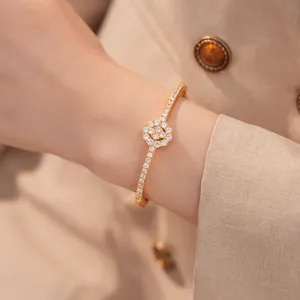 Detailansicht eines 18K vergoldeten Zirkonia-Blumenarmreifs, getragen an einem Handgelenk