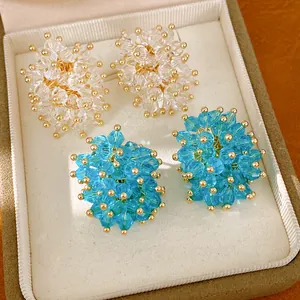 Detailed view of clustered glass bead stud earrings with gold accents inside a jewelry box.