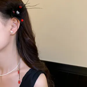 Primo piano di un fermaglio per capelli a fiori scuri con nappe a goccia rosse e catene lunghe.