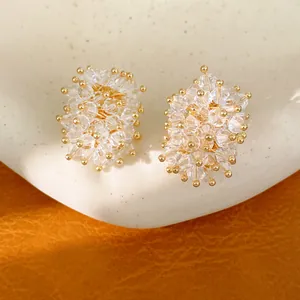 Close-up of elegant crystal cluster stud earrings with gold accents on a white display stand