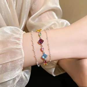 Close-up detail of a sweet colorful zircon geometric bracelet worn on a wrist with silk