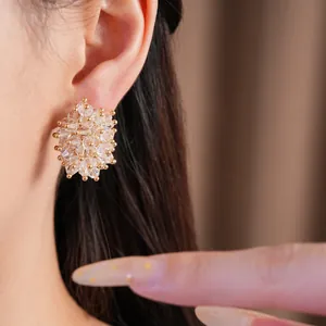 Detail view of elegant clear glass bead cluster stud earrings with gold accents worn on ear