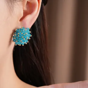 Detailed view of elegant blue crystal flower stud earrings with silver posts worn on ear