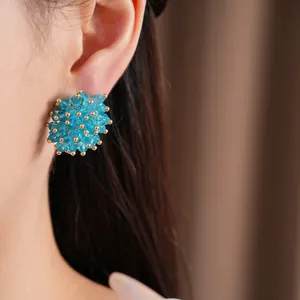Detailed view of an elegant blue faceted glass bead cluster stud earring on an Asian model's ear