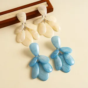 Detailed macro view of retro resin earrings with blue and cream marble teardrop pendants.
