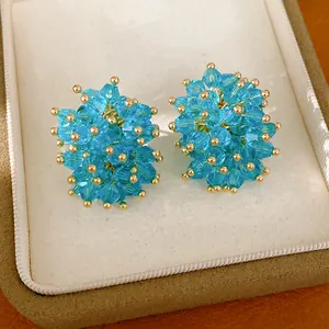 Detailed view of sky blue crystal bead stud earrings in a luxury cream jewelry box