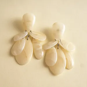 Close-up of retro marbled resin teardrop earrings with cream color and tassel design